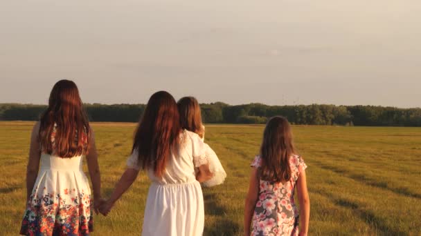 Happy young family with a child walking on a summer field. concept of happy family and childhood. Children and mom are playing in the meadow. mother and little daughter with sisters walking in park. - Footage, Video