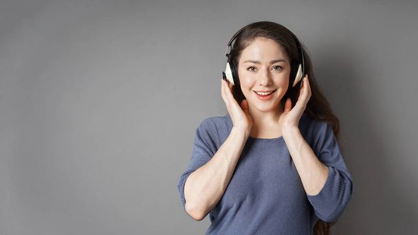 счастливая улыбающаяся молодая женщина слушает музыку в наушниках
 - Фото, изображение