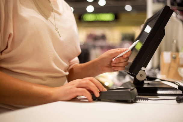 Mujer joven escaneando las manos, introduciendo descuento, venta en un recibo, caja registradora con pantalla táctil, tienda de mercado
 - Foto, Imagen