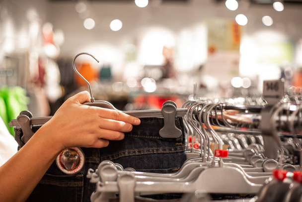Mujer joven eligiendo la ropa en el enorme centro comercial durante las grandes ventas
 - Foto, imagen