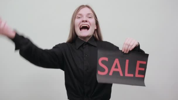 Happy blonde woman showing tongue, keeping advertising sale, smiling - Imágenes, Vídeo