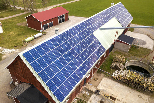 Vista superior do sistema de painéis solares fotovoltaicos azuis no edifício de madeira, celeiro ou telhado da casa. Conceito de produção de energia verde ecológica renovável
. - Foto, Imagem