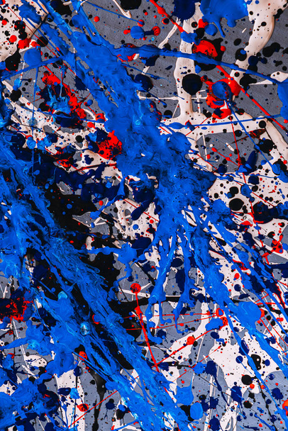 Picture painted using the technique of dripping. Mixing different colors blue red white black. A riot of color. Lines and spots. Vertical orientation. - Photo, Image
