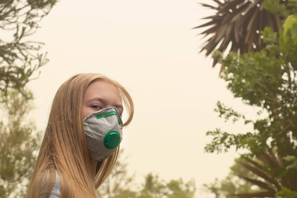 Австралійська лісова пожежа: блондинка, одягнена в протипожежну маску P2 N95, щоб зменшити кількість дихання Pm2.5 з диму.. - Фото, зображення