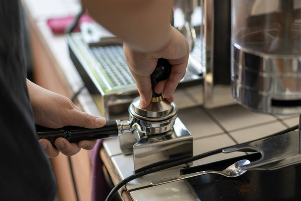 Barista apisonada café molido en un portafilter
 - Foto, Imagen
