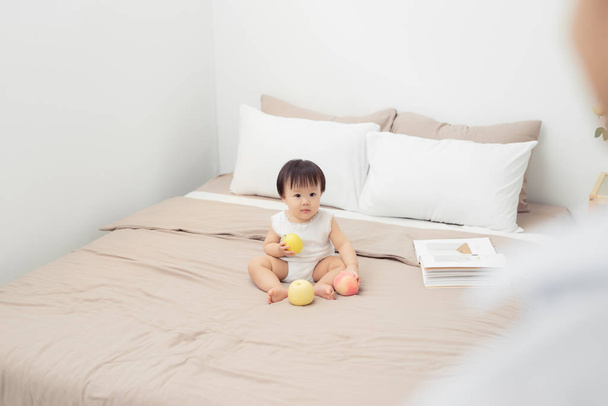 Cute baby playing with toy on bed. Kid playing at home - Photo, Image