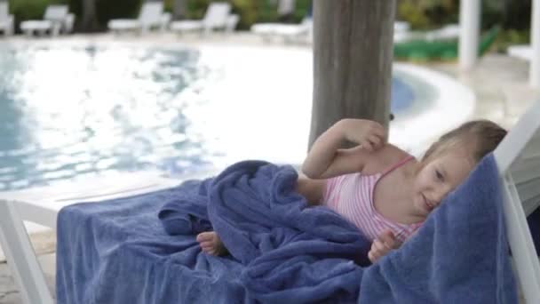 Una niñita yace en un Chaise junto a la piscina infantil
 - Metraje, vídeo