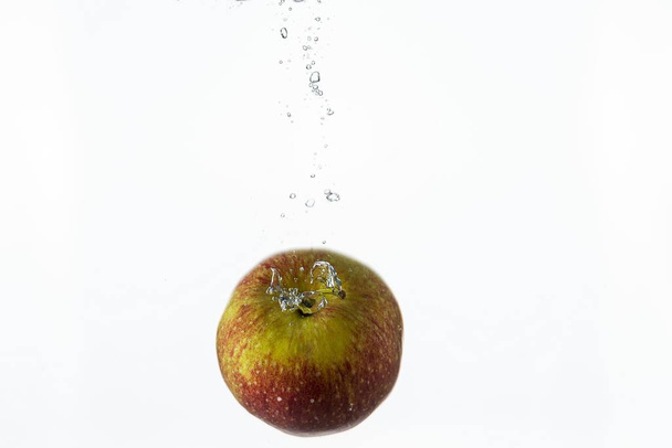 Close up view splashing water and red apple on white background. Beautiful backgrounds. - Foto, Imagen