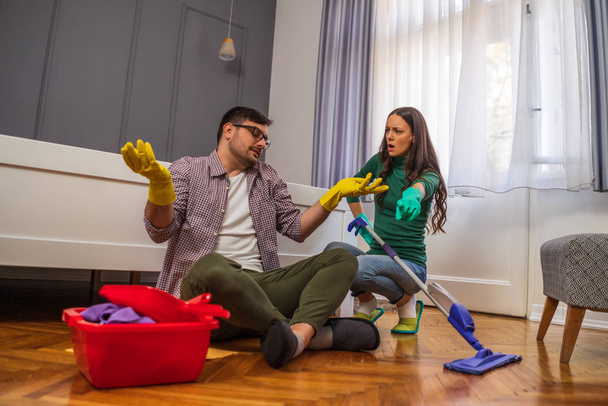 男は怠け者だ。彼の妻は彼らのアパートを掃除し続けるように言っている.  - 写真・画像