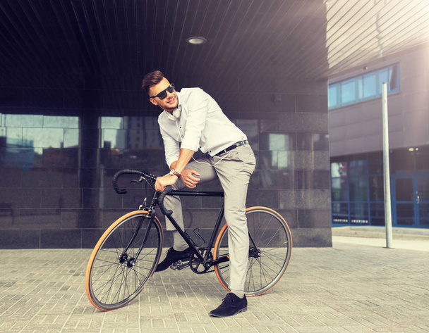 man with bicycle and headphones on city street - Fotó, kép