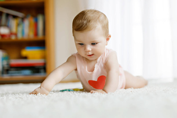 Little funny baby girl lifting body and learning to crawl. - Foto, Bild
