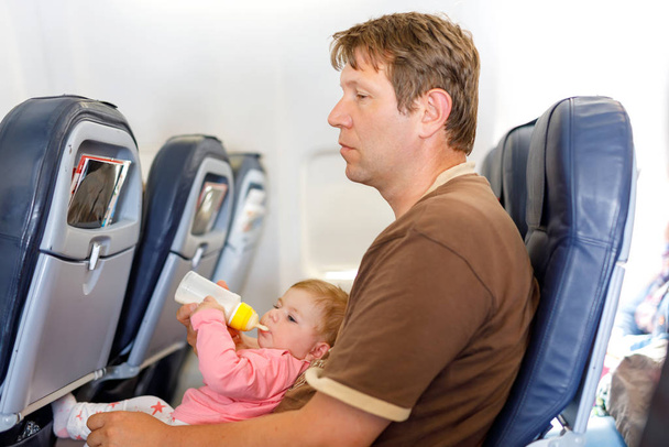 Vader zijn baby dochter houden tijdens de vlucht op het vliegtuig op vakantie te gaan - Foto, afbeelding