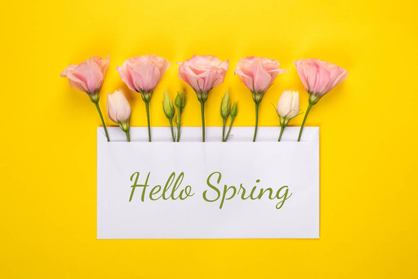 Helló, tavaszi zászló. Rózsaszín Eustoma virágok elrendezése üres kártya sárga alapon - Fotó, kép