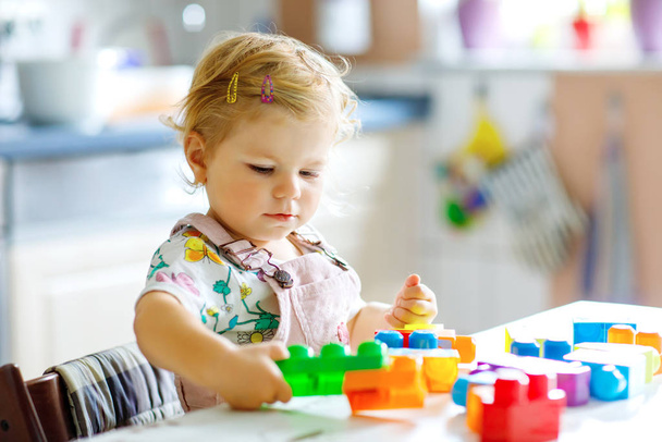 Чарівна дівчинка-малюк грає з освітніми іграшками в дитячій кімнаті. Щаслива здорова дитина розважається з різними пластиковими блоками вдома. Мила дитина вчиться створювати і будувати
. - Фото, зображення