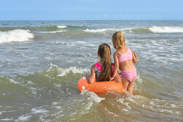 Los niños juegan con anillo de piscina en la playa del mar y hermoso horizonte
. - Foto, Imagen