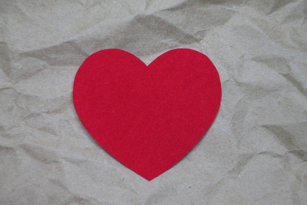Red paper heart on a paper craft background. - Foto, afbeelding
