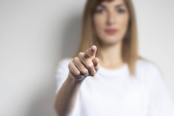 Young woman points a finger at something on a light background - Photo, Image