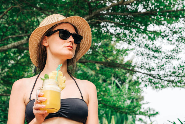 Relaxed woman in bikini drinking pineapple cocktail - Fotografie, Obrázek