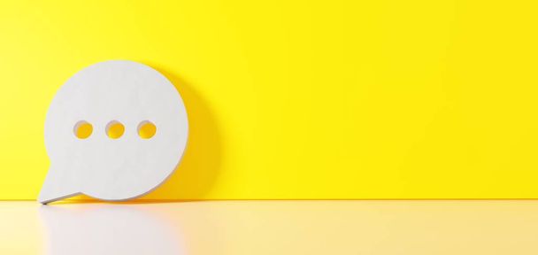 Renderização 3D do símbolo branco do ícone de bolha de bate-papo arredondado apoiado na parede de cores com reflexão no chão com espaço vazio no lado direito
 - Foto, Imagem