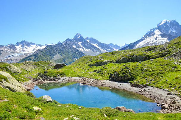 Lodowiec Lac de Cheserys, jezioro Cheserys niedaleko Chamonix-Mont-Blanc w Alpach Francuskich. Alpejskie jezioro ze śnieżnymi górami w tle. Szlak Tour du Mont Blanc. Alpy w sezonie letnim - Zdjęcie, obraz