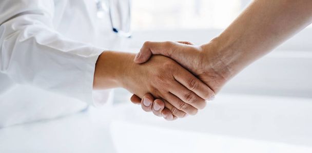 Female doctor shaking hands with man in medical office - Photo, Image