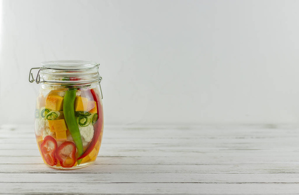 glass jar of fermented vegetables on a light background. fermentation is a source of probiotics - Photo, Image