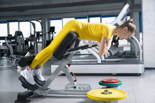 junge sportliche Frau trainiert im Fitnessstudio an einem Trainingsgerät - Foto, Bild