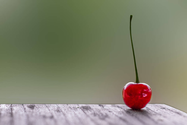 Cherry on wooden table with blurred background - 写真・画像