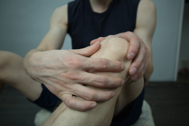 dor aguda de um joelho de um homem jovem durante mãos de massagem de aptidão de esportes
 - Foto, Imagem