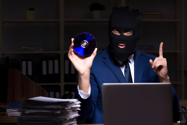Hombre empleado robando información en la oficina durante la noche
 - Foto, imagen