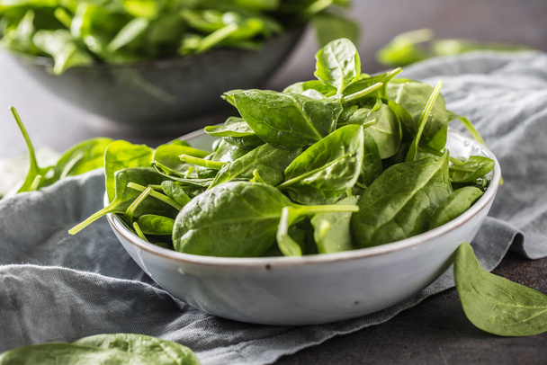 Fresh baby spinach in bowl on dark kitchen table - Photo, image