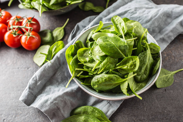 Fresh baby spinach in bowl on dark kitchen table - Photo, image