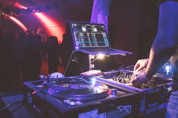 Крупним планом DJ поворотний стіл, з людьми танцюють на задньому плані
 - Фото, зображення