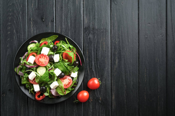 Salada de legumes frescos com feta, azeitonas e ervas em uma placa escura em um fundo rústico escuro. Comida vegetariana saudável. Espaço de cópia da vista superior
. - Foto, Imagem