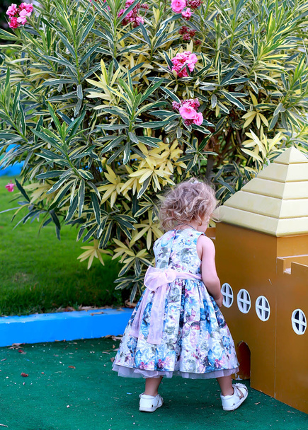 Kız, oyun parkındaki küçük kahverengi bir evin yanında oynuyor.  - Fotoğraf, Görsel