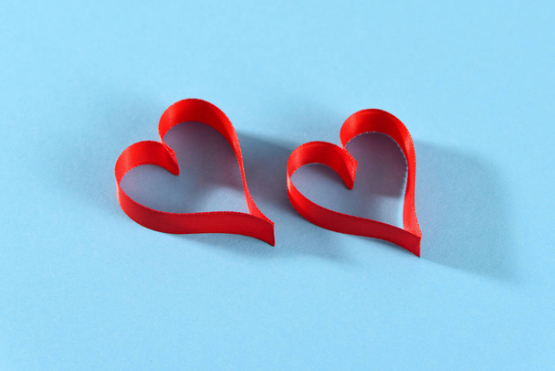 Два красных сердца на бирюзовом фоне, концепция любви ко Дню Святого Валентина
 - Фото, изображение