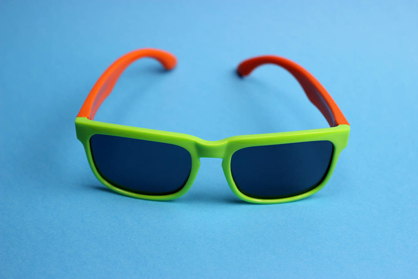 Дитячі кольорові сонцезахисні окуляри на синьому фоні
 - Фото, зображення