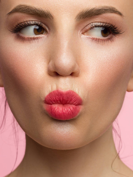 Close-up of a female portrait with a towel on her head and evening make-up. Arrows in the eyes and extremely long eyelashes. Makes a kiss on camera. Clean skin and pink lips. Thick even eyebrows - Foto, imagen