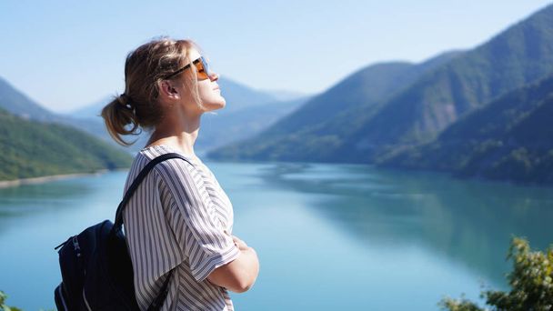 Smiling woman against mountain landscape and lake - Foto, imagen