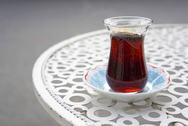 Served tea on a turkish tea glass on a metal cafe table at street. - Photo, Image