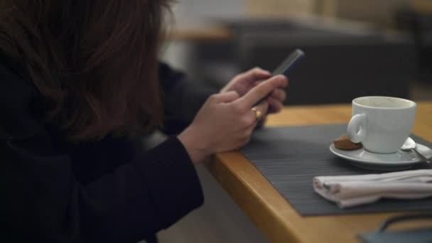 Pan ujęcie kobiety pijącej filiżankę kawy pijącej przez telefon - Materiał filmowy, wideo