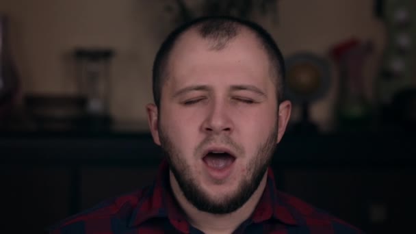 A young guy of European appearance in a plaid shirt closeup yawns. The concept of emotions - Footage, Video