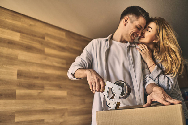 Attractive lovely couple packing a cardboard box to move into ne - Foto, imagen