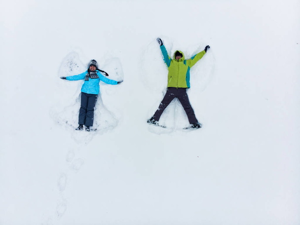 casal se divertindo fazendo anjo da neve
 - Foto, Imagem