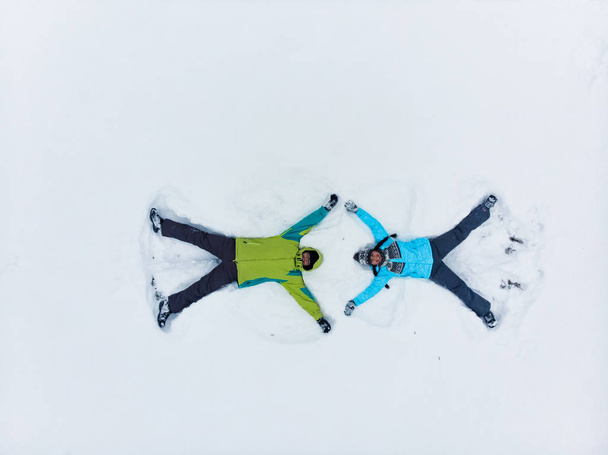 пара весело делает снежного ангела
 - Фото, изображение