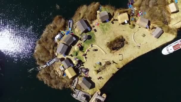 ペルーの空中ドローン上面に浮かぶウロス島。フローティングアイランドはティティカカ湖の浅瀬にあるトトラの切り立った層からウロス人によって建設された小さな人工島です。. - 映像、動画