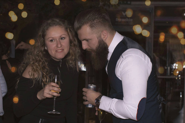 12.13.2019 Szlovákia. Nyitra. Egy lány egy férfival poharakból iszik. Lány és férfi egy partyon.Férfiak és nők ünneplő születésnapi vagy újévi party . - Fotó, kép