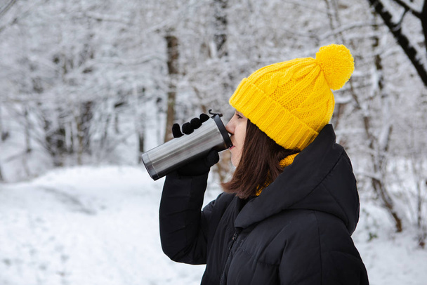 жінка в зимовому вбранні п'є теплий напій з чашки, що переплавляється
 - Фото, зображення