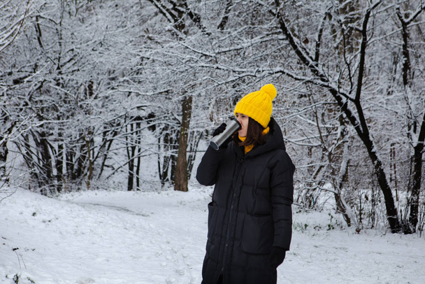 woman in winter outfit drinking warm up drink from refillable mug - Photo, Image