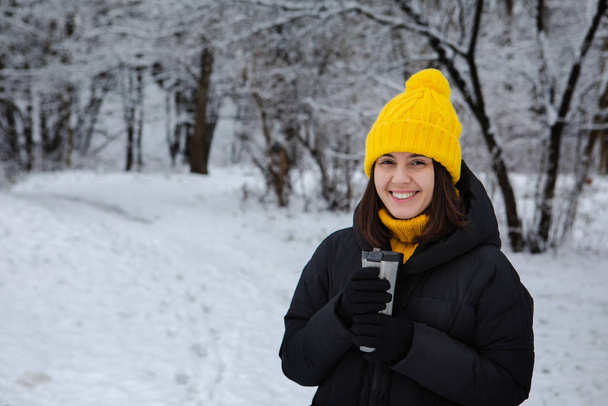 donna sorridente in abito invernale bere bevanda di riscaldamento da tazza ricaricabile
 - Foto, immagini